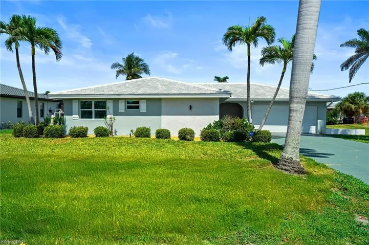 Ranch-style house featuring driveway, stucco siding, a front yard, and a garage. Virtually edited image.