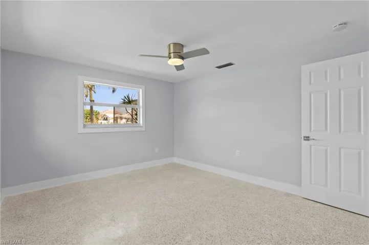 Empty room with visible vents, baseboards, a ceiling fan, and terrazzo floor. Virtually edited photo.