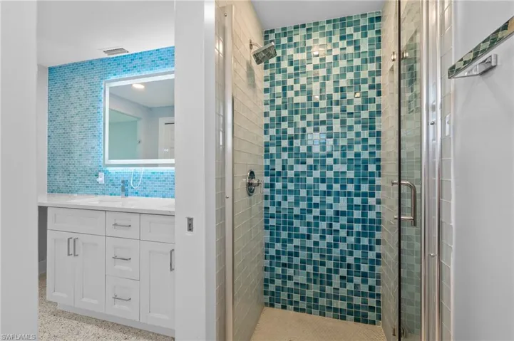 Full bath with tasteful backsplash, vanity, a stall shower, visible vents, and terrazzo floor.  Virtually edited image.