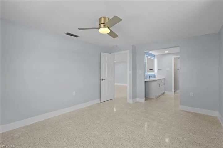 Unfurnished bedroom with visible vents, baseboards, terrazzo floor, and a ceiling fan. virtually edited image.