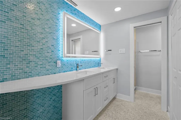 Full bath featuring baseboards, terrazzo floor, a sink, and visible vents. Virtually edited photo.