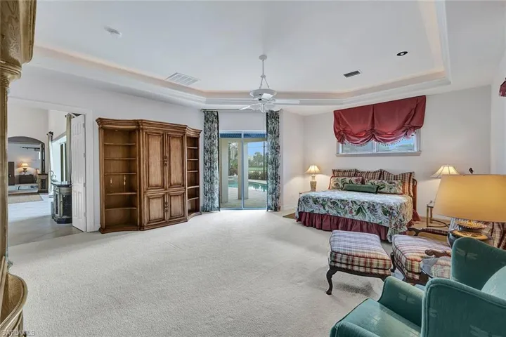 Carpeted bedroom featuring ceiling fan, a raised ceiling, and access to outside
