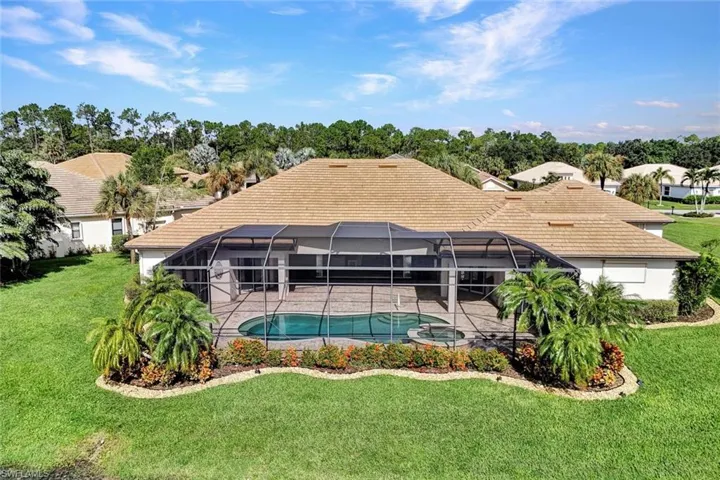 Rear view of house featuring a lanai and a lawn