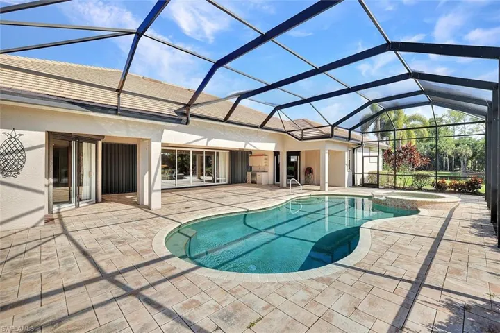 View of swimming pool featuring glass enclosure and a patio