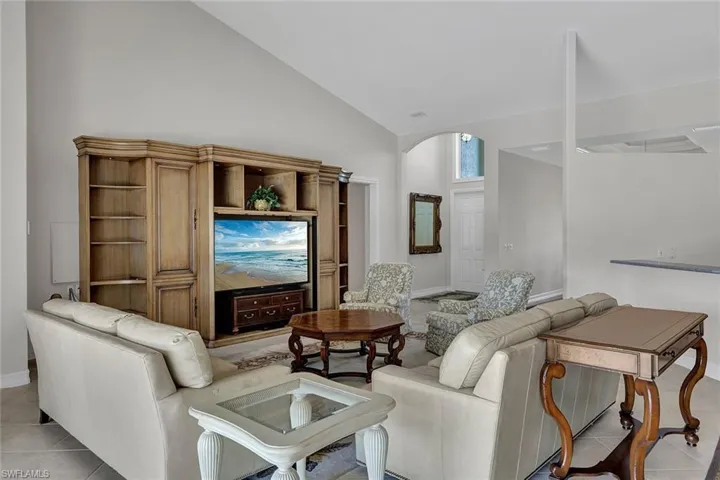 Tiled living room featuring high vaulted ceiling