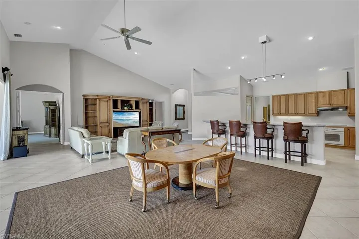 Dining space with ceiling fan, high vaulted ceiling, and light tile patterned floors