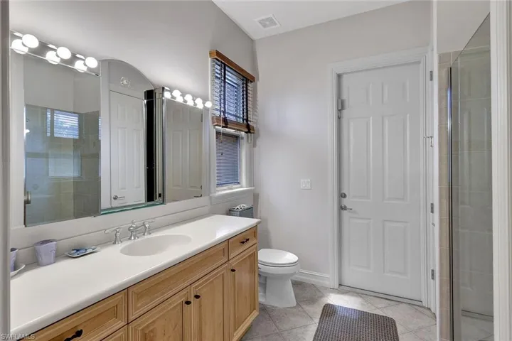 Bathroom with a healthy amount of sunlight, toilet, tile patterned floors, vanity, and a shower with shower door