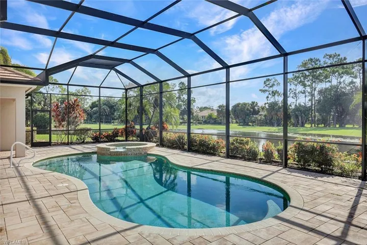 View of pool with an in ground hot tub, a patio, and glass enclosure