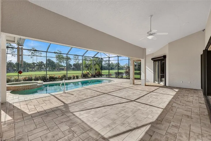 View of swimming pool with ceiling fan, an in ground hot tub, a patio area, and a lanai