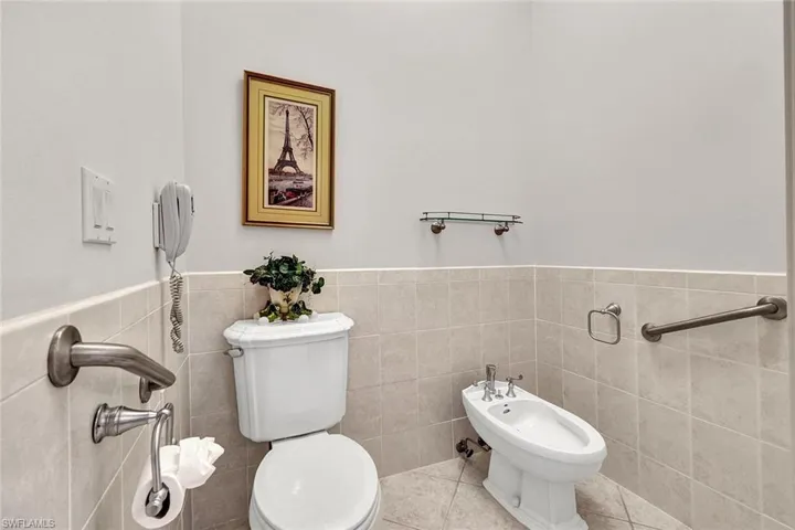 Bathroom featuring tile walls, toilet, tile patterned floors, and a bidet