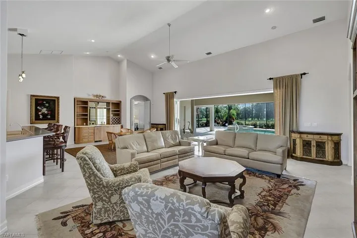 Tiled living room featuring high vaulted ceiling and ceiling fan