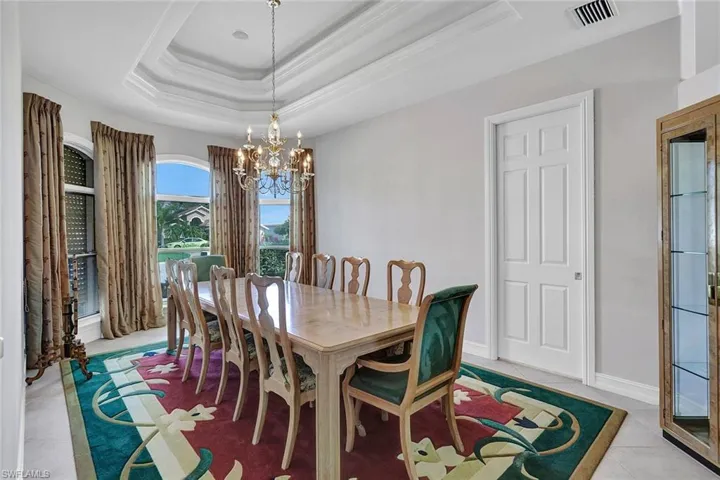 Dining space with a raised ceiling, light tile patterned flooring, and a chandelier