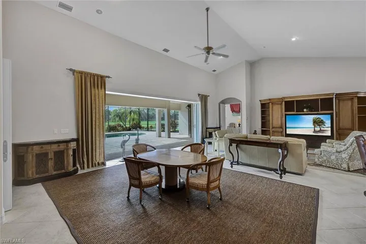 Tiled dining area featuring ceiling fan and high vaulted ceiling