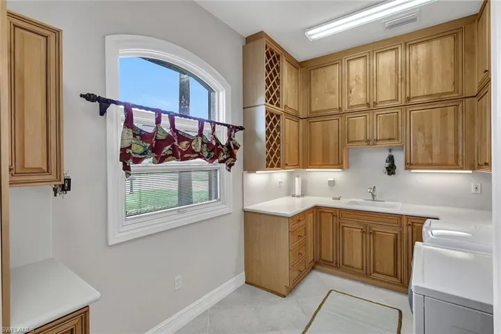 Kitchen featuring washer / clothes dryer, light tile patterned flooring, and sink