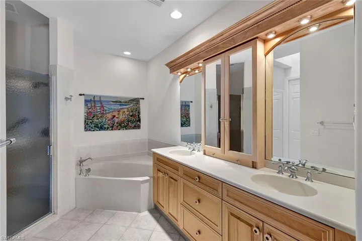Bathroom featuring shower with separate bathtub, dual bowl vanity, and tile patterned flooring