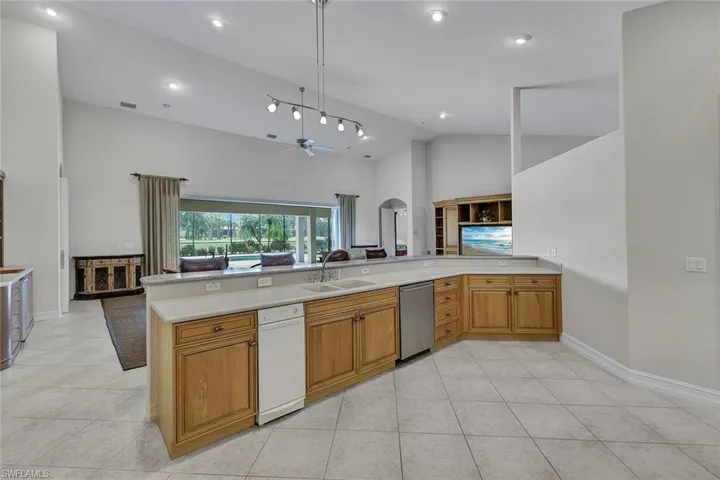 Kitchen featuring light tile patterned floors, white dishwasher, ceiling fan, sink, and kitchen peninsula
