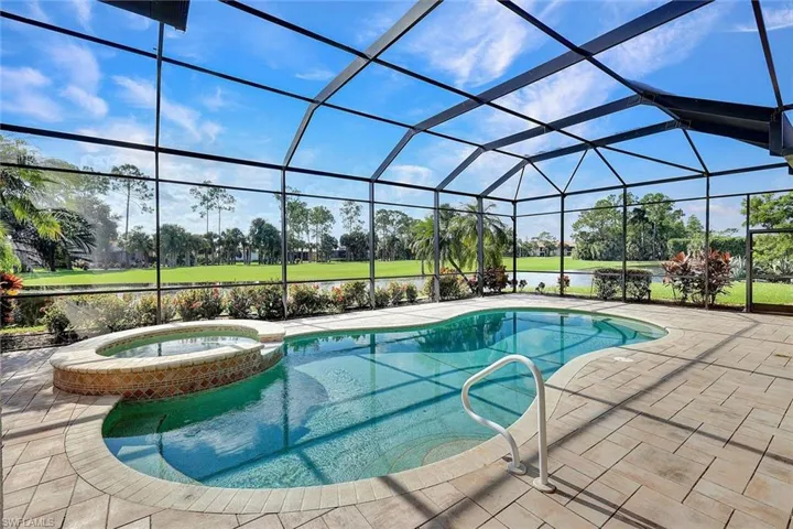 View of pool with glass enclosure, an in ground hot tub, and a patio