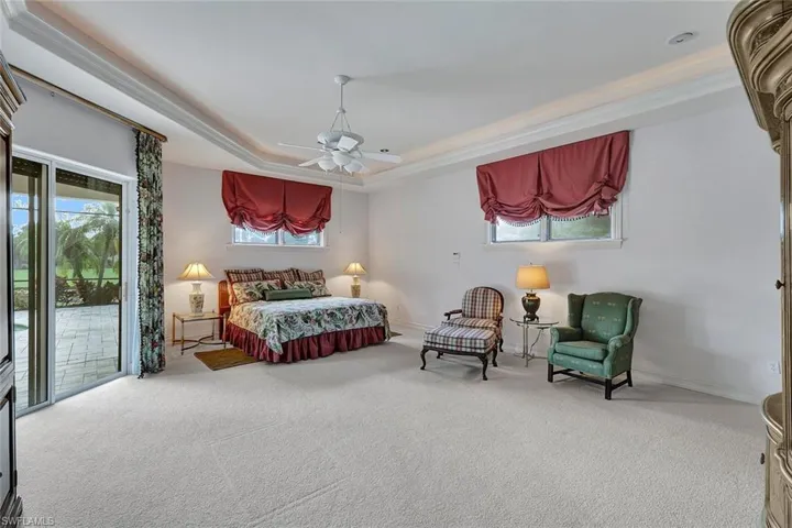 Carpeted bedroom featuring a raised ceiling, multiple windows, and access to exterior