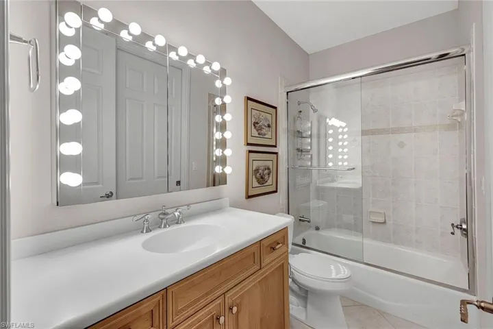 Full bathroom featuring tile patterned floors, vanity, bath / shower combo with glass door, and toilet