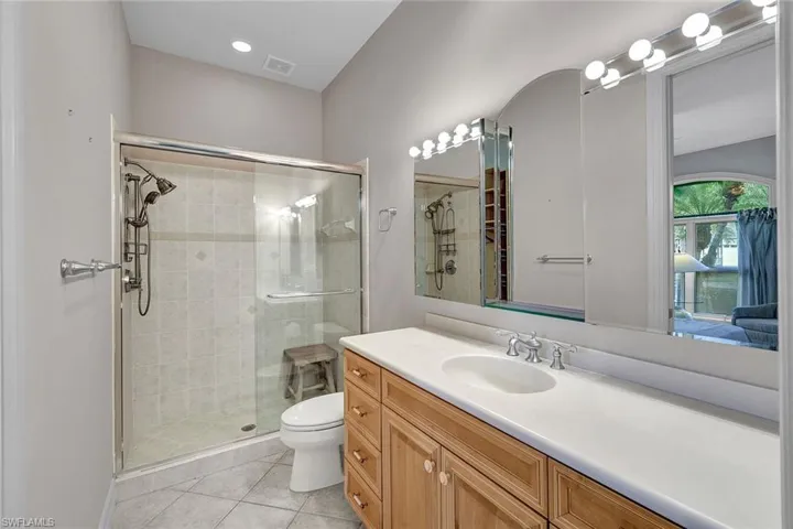 Bathroom featuring tile patterned floors, vanity, a shower with door, and toilet