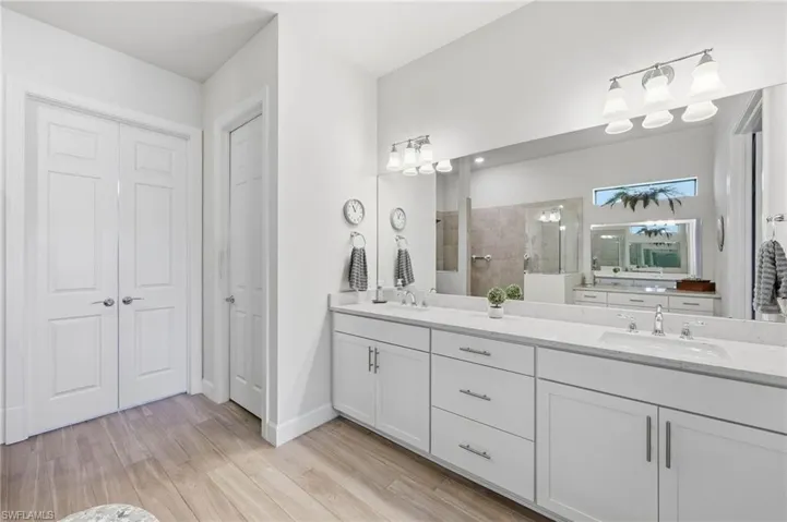Expansive vanity with dual undermount sinks, white cabinetry, private water closet and double doors into your spacious walk in closet