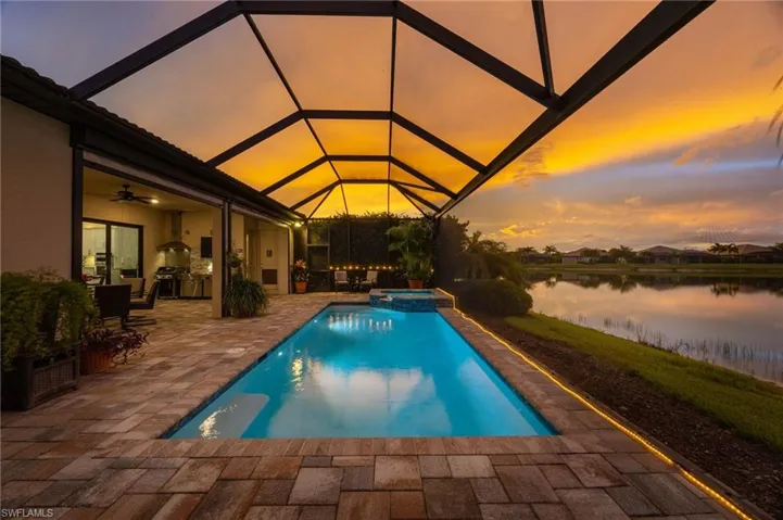 Sunset from the enclosed pool area and covered outdoor kitchen/ dining  area, all overlooking a tranquil body of water