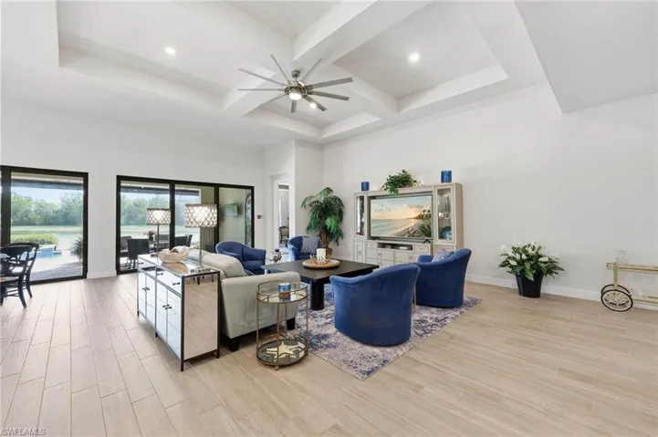 Spacious interior great room  featuring a tiered tray ceiling with a ceiling fan, recessed lighting, and light tile flooring, great space to entertain