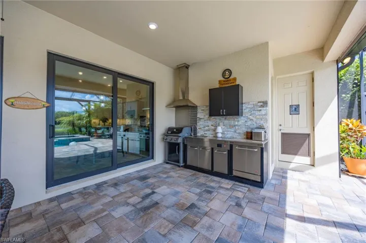 Rear covered lanai  patio featuring a built-in outdoor kitchen with storage closet and pool bath