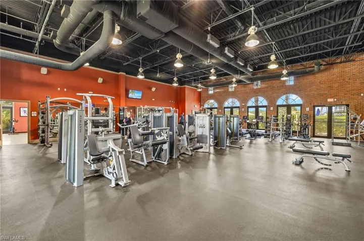 Workout area with a high ceiling, brick wall, french doors, and rail lighting
