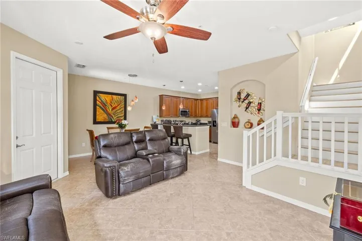 Living area featuring stairway, light tile patterned flooring, a ceiling fan, baseboards, and recessed lighting