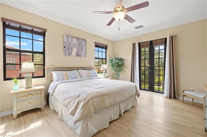 Bedroom with baseboards, light wood-style flooring, crown molding, french doors, and a ceiling fan