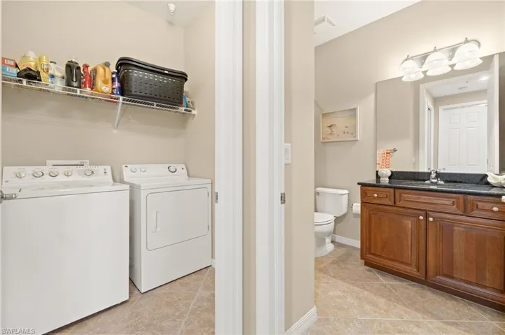 Laundry area featuring washer and dryer, light tile patterned flooring, and baseboards