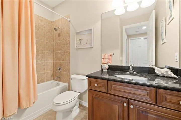 Full bath featuring shower / bathtub combination with curtain, toilet, vanity, and tile patterned floors