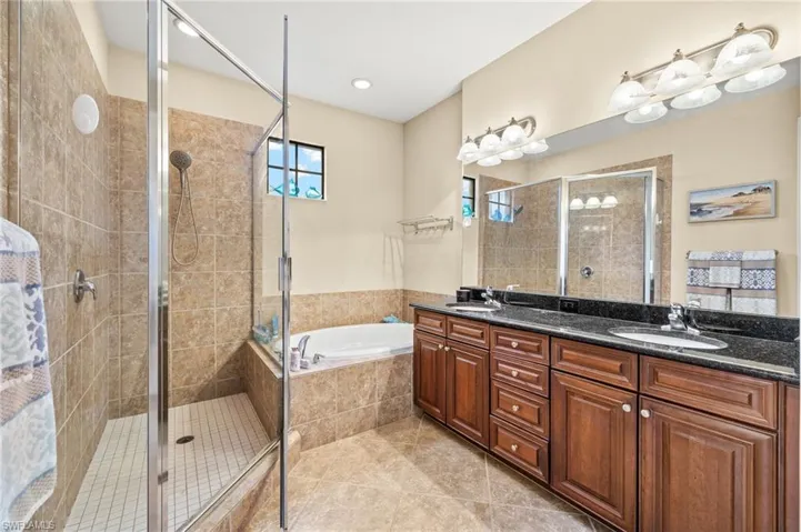 Full bath with a stall shower, a bath, tile patterned flooring, and double vanity