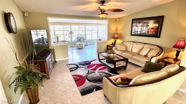 Living area featuring light tile patterned floors, a textured ceiling, and a ceiling fan