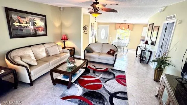 Living room with light tile patterned floors, a textured ceiling, and ceiling fan