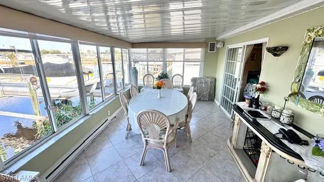 Sunroom with a baseboard heating unit, a water view, and tile patterned floors
