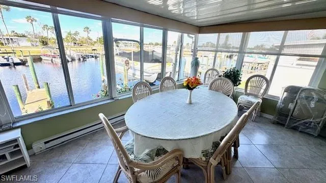 Sunroom / solarium featuring a baseboard heating unit, healthy amount of natural light, and a water view