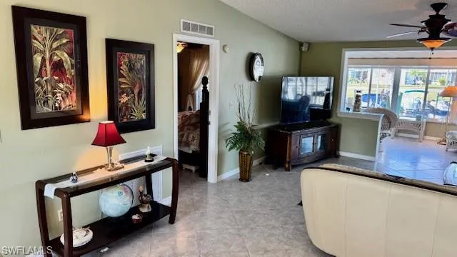 Living area featuring a ceiling fan, a textured ceiling, and light tile patterned floors