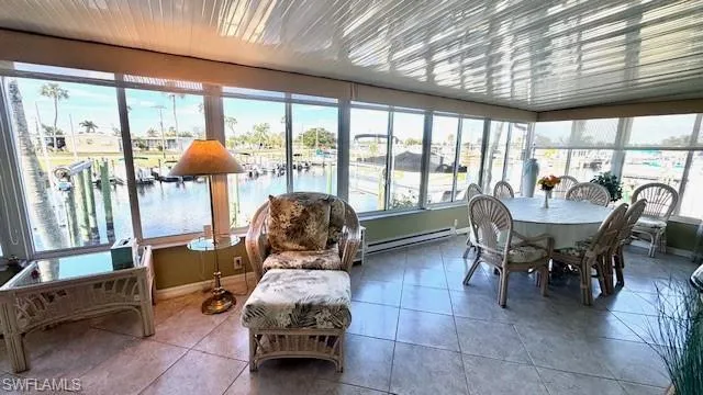 Sunroom featuring a water view, baseboard heating, and tile patterned floors