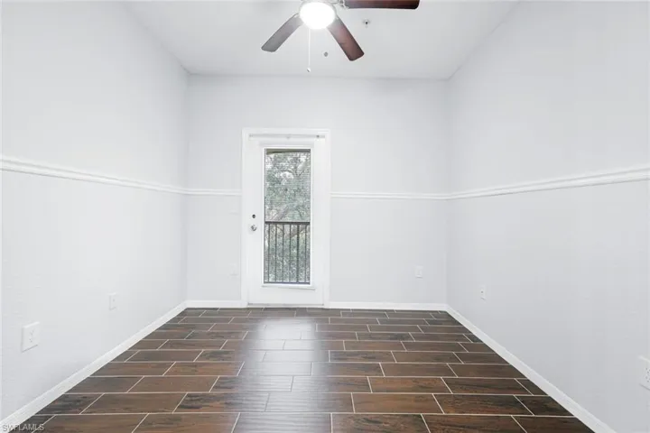 Empty room with ceiling fan and dark hardwood / wood-style floors