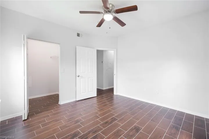 Empty room featuring dark wood-type flooring and ceiling fan