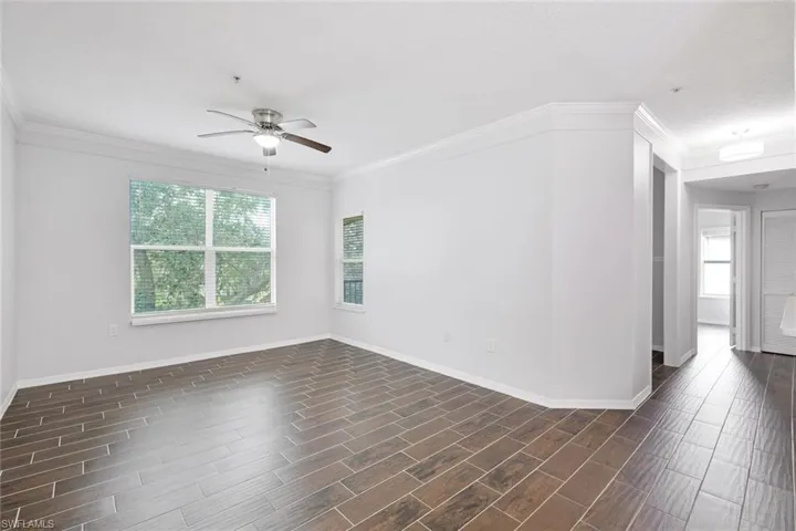 Unfurnished room featuring crown molding, dark hardwood / wood-style floors, and ceiling fan