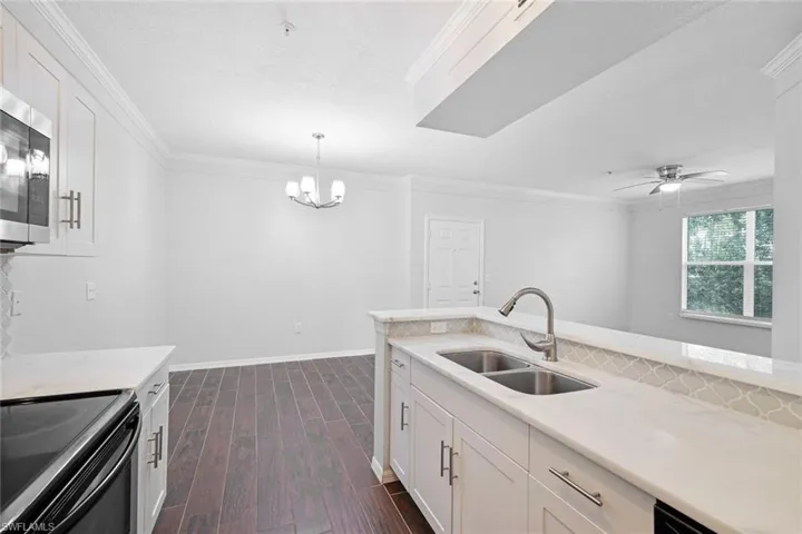 Kitchen featuring electric range, sink, white cabinets, and dark wood-type flooring