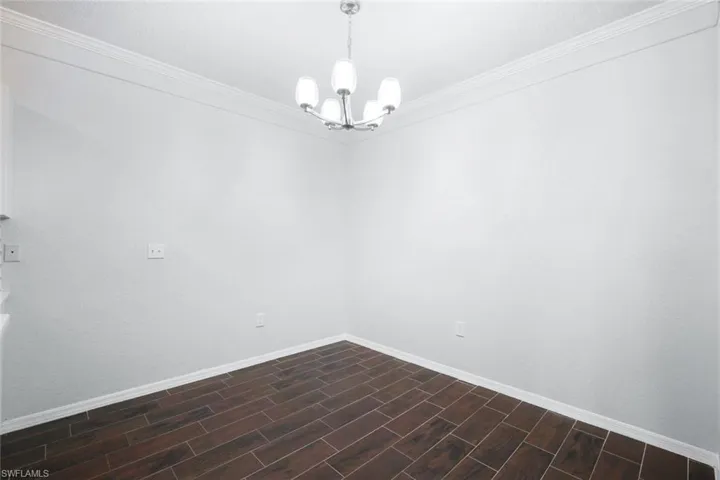 Unfurnished room with crown molding, a chandelier, and dark hardwood / wood-style floors