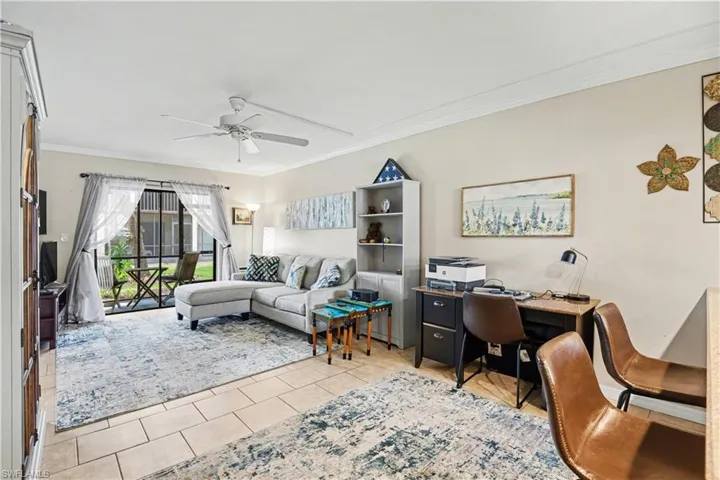 Living are with ornamental molding, a ceiling fan, and light tile patterned floors