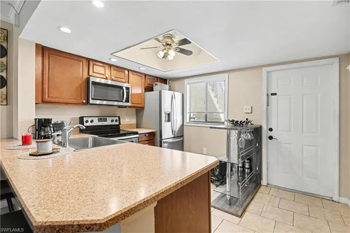 Kitchen featuring wood finish cabinetry, a peninsula, stainless steel appliances, a ceiling fan, and recessed lighting
