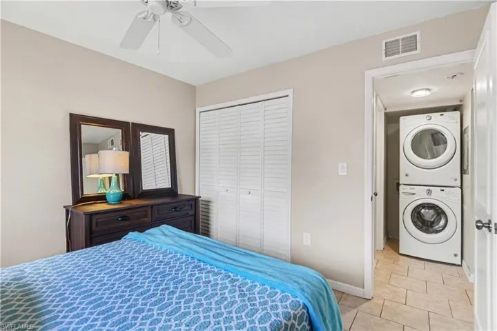 Bedroom featuring stacked washer / dryer, a closet, ceiling fan, and light tile patterned floors