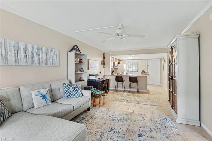 Living area featuring crown molding, a ceiling fan, and light tile patterned floors