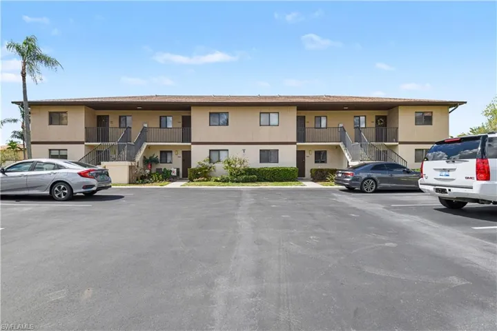 View of apartment building / complex with stairs and uncovered parking